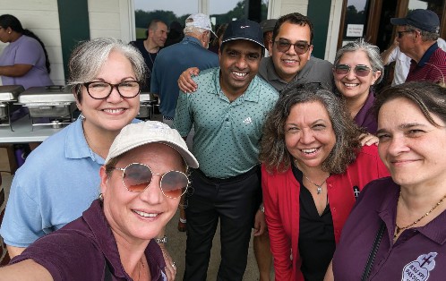 Elsie Hernandez in a bright red blazer surrounding by smiling colleagues.