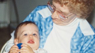 A happy baby in the lap of an elderly woman.