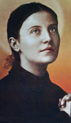 St. Gemma with a halo-like glow behind her head, dressed in Passionist habit, gazes upward with a serene expression and clasped hands, evoking a prayerful or saintly pose.