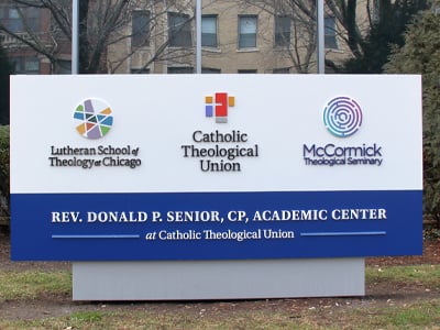 A large outdoor sign for the "Rev. Donald P. Senior, CP, Academic Center" at Catholic Theological Union, displaying logos for the Lutheran School of Theology at Chicago, Catholic Theological Union, and McCormick Theological Seminary.