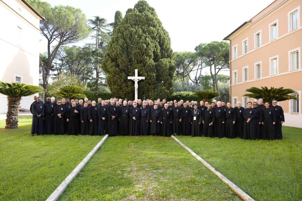 Large group of Passionist priests and brothers outside in Rome in front of a crucifix
