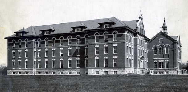 Historic black-and-white photograph of the Immaculate Conception Monastery in 1910, a large brick and stone building with arched windows, gabled roofs, and a chapel wing on the right.