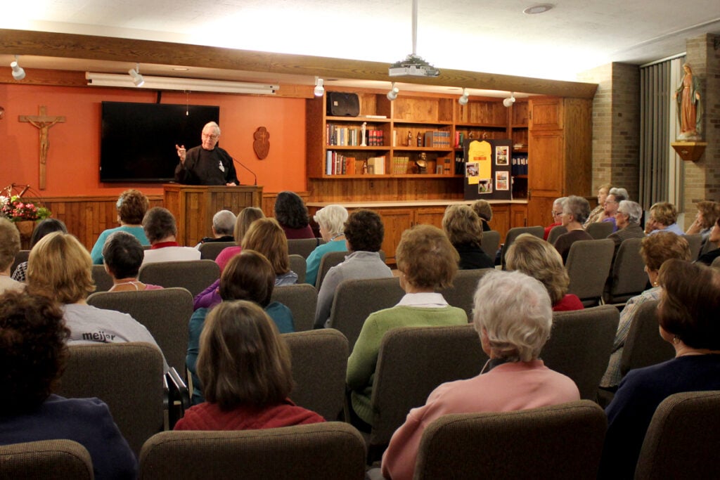 Fr. Pat Brennan, CP, preaches behind a podium at a women's retreat in Detroit.