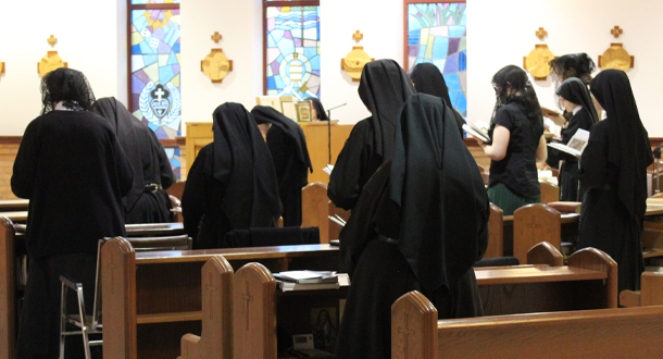 Catholic sisters in black habits praying at Mass