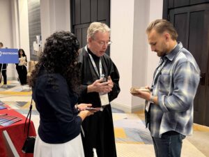 A Passionist priest and two conference stand in prayer with their heads bowed.