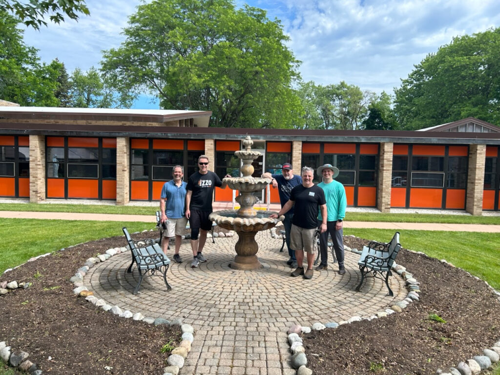 Smiling male volunteers spruce up the courtyard at a Passionist retreat center