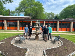 Smiling male volunteers spruce up the courtyard at a Passionist retreat center
