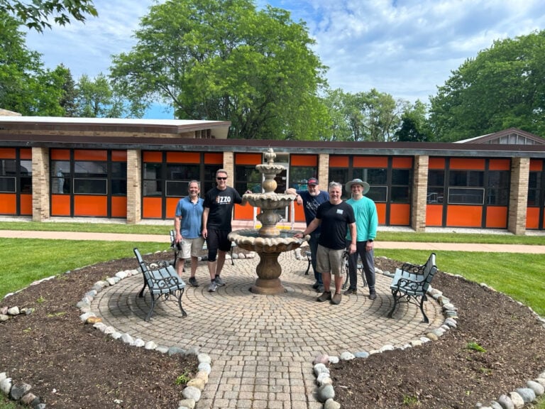 Smiling male volunteers spruce up the courtyard at a Passionist retreat center