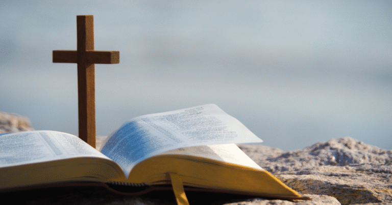 The Bible and a cross on the sand by the ocean