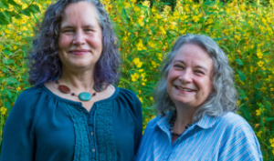 Two smiling women pose in front of natural greenery as they assume the positions of Co-Directors of the Passionist Earth & Spirit Center
