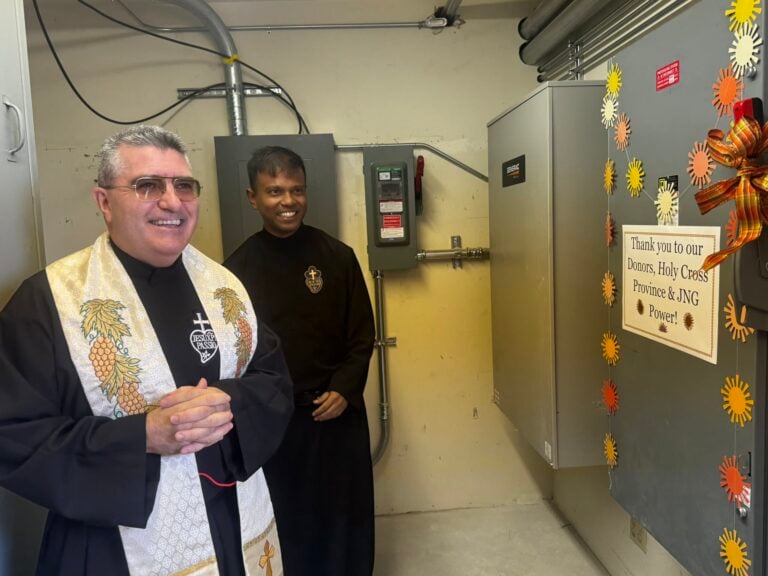 Two Passionist priests excitedly turn on a solar panel system for the first time